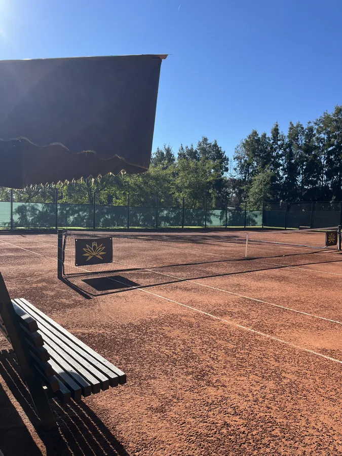 Cancha de tenis con banco y tribuna