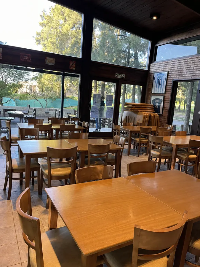 Interior del quincho con mesas y sillas de madera